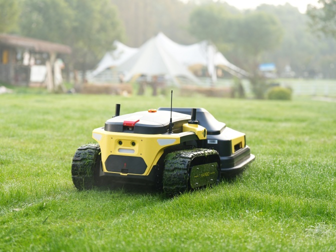 Ein gelber Mähroboter fährt über eine kurz gemähte Wiese