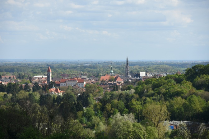Eine Stadt aus der Ferne fotografiert, zwischen bewaldeten Hügeln gelegen.