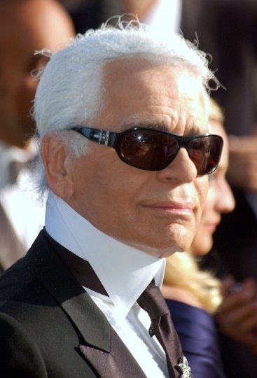 Karl Lagerfeld mit großer, dunkler Sonnenbrille und weißen, zum Zopf gebundenen Haaren
