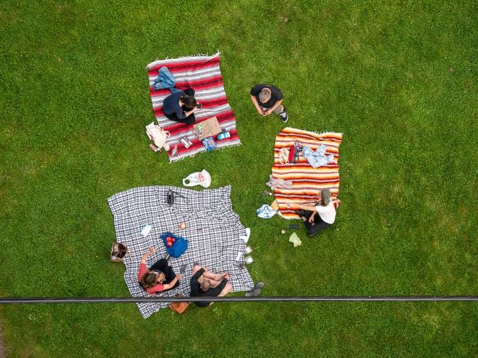 Eine Luftaufnahme von Menschen, die auf 3 Decken auf einer Wiese picknicken