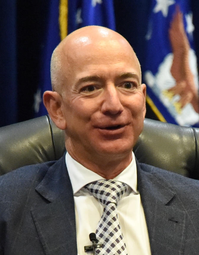 Jeff Bezos mit Glatze in grauem Anzug und mit Krawatte.
