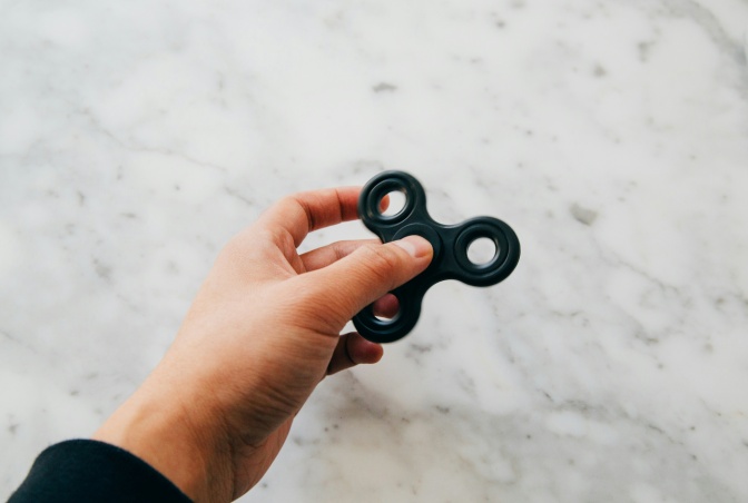Eine Hand mit einem schwarzen Fidget Spinner