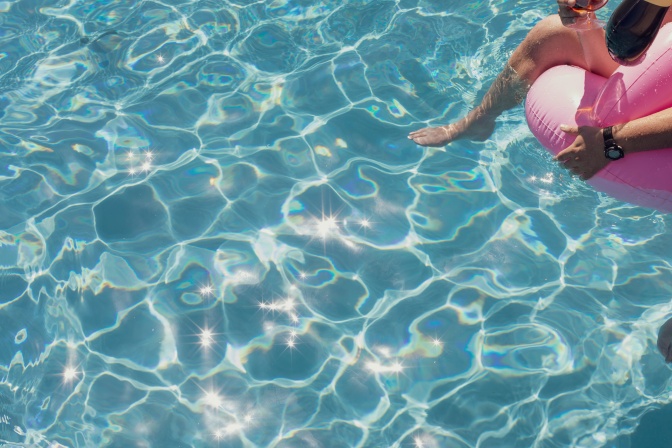 Eine Person treibt in einem rosafarbenen Schwimmring durch einen Pool.