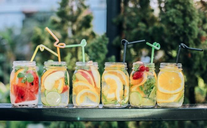 6 bunte Cocktails mit verschiedenen Früchten stehen nebeneinander.