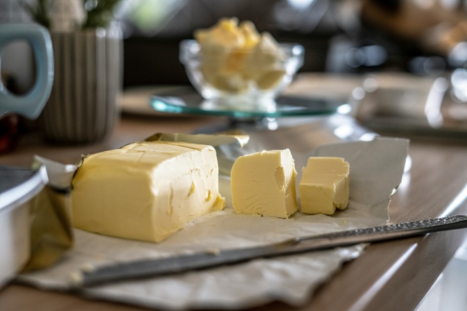 Ein Block Butter, von dem 2 kleinere Stücke abgeschnitten wurden.