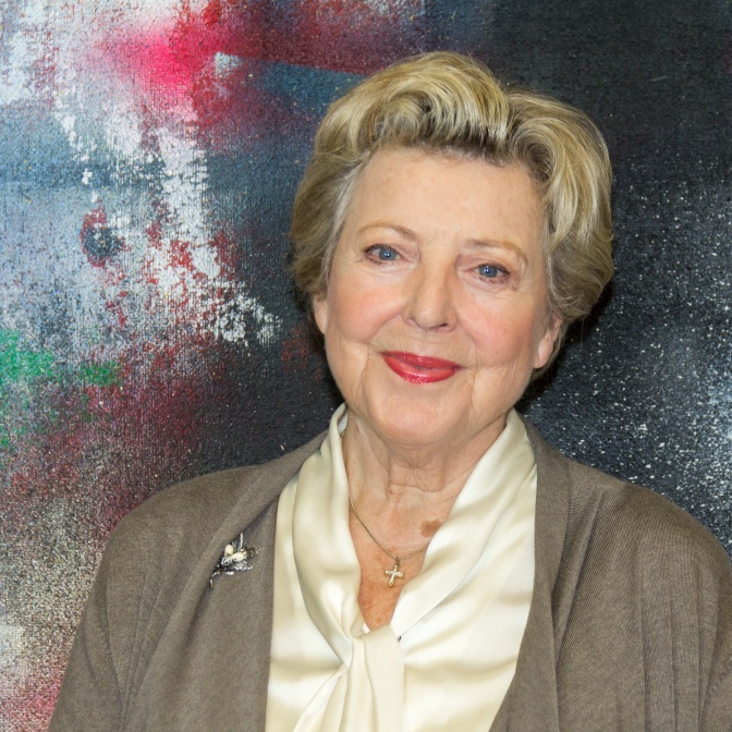 Marie-Luise Marjan mit rotem Lippenstift und kurzen blonden Haaren. Sie lächelt in die Kamera.