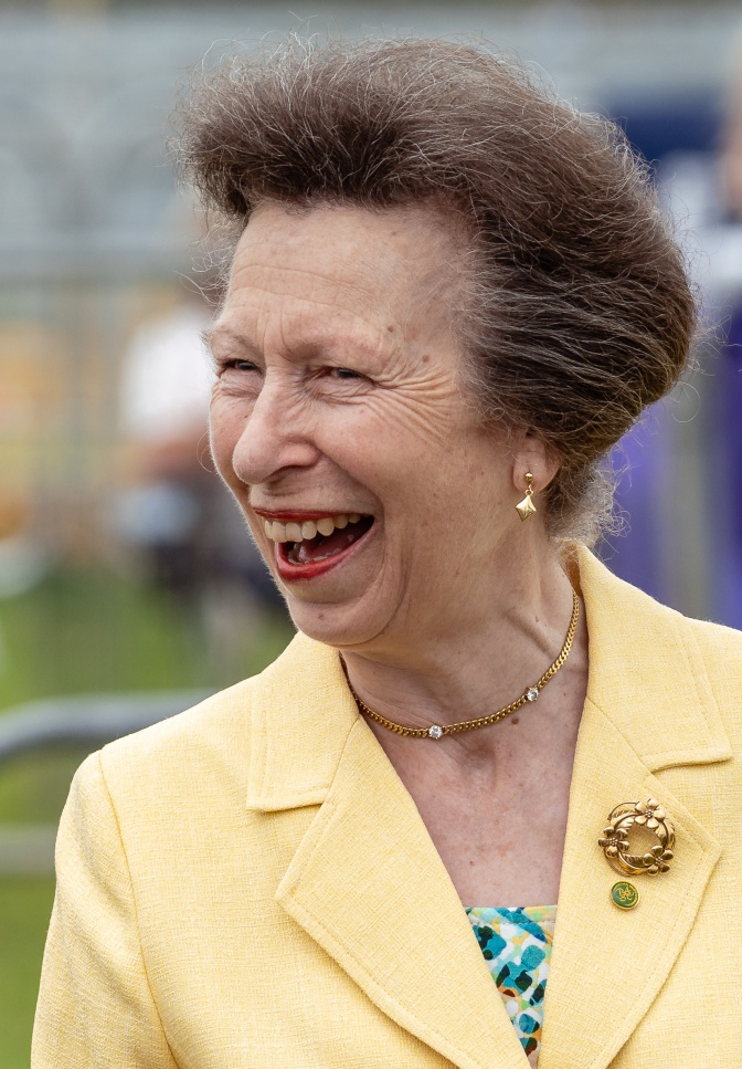 Prinzessin Anne lachend in einem hellgelben Kostüm und mit hochgesteckten Haaren.