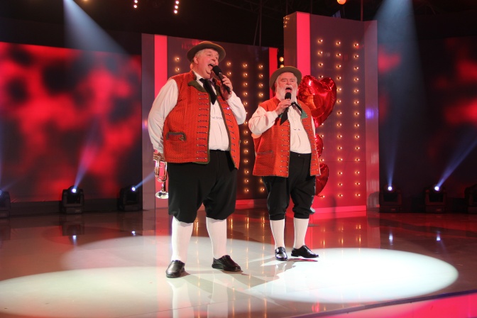 Die Wildecker Herzbuben in Tracht auf der Bühne. Beide singen in ein Mikrofon.