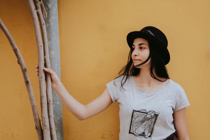 Eine Frau mit langen Haaren und einem schwarzen Hut in einem schwarz-weißen Shirt.