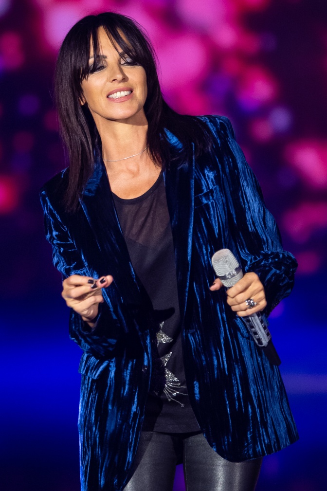 Nena auf der Bühne in einem blauen Samtblazer und mit Mikro in der Hand.