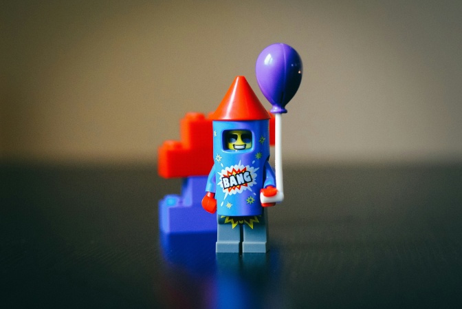 Eine Legofigur als Rakete verkleidet mit einem lilafarbenen Luftballon in der Hand