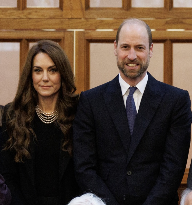 Prinz William und Prinzessin Kate in formeller schwarzer Kleidung. Sie sitzen nebeneinander und schauen direkt in die Kamera.