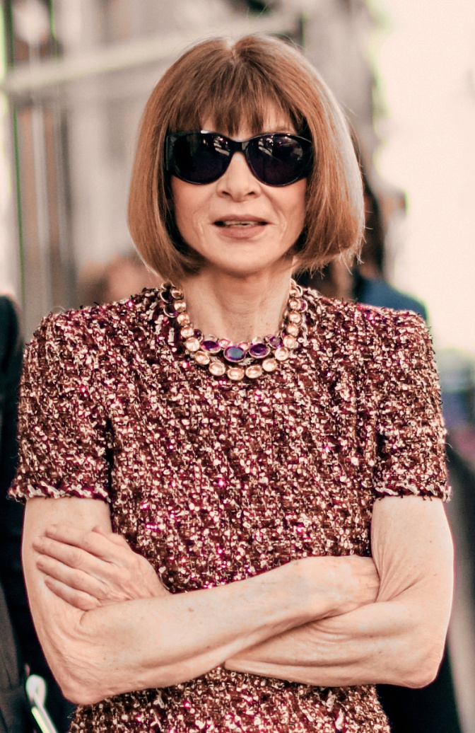 Anna Wintour mit einer großen schwarzen Sonnenbrille in einem gemusterten kurzärmligen Kleid
