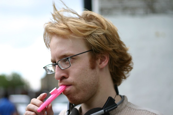 Ein Mann spielt auf einer roten Kazoo aus Plastik.