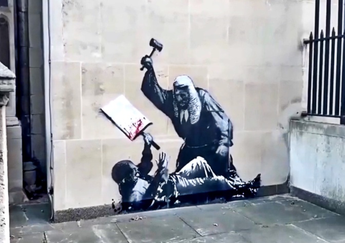 Ein auf eine Wand gespraytes Kunstwerk in schwarz-weiß zeigt einen Richter, der mit einem Hammer auf einen Demonstranten einschlägt.