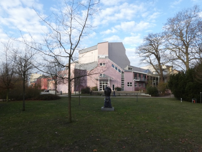 Ein rosafarbenes Gebäude mit großen Fenstern.