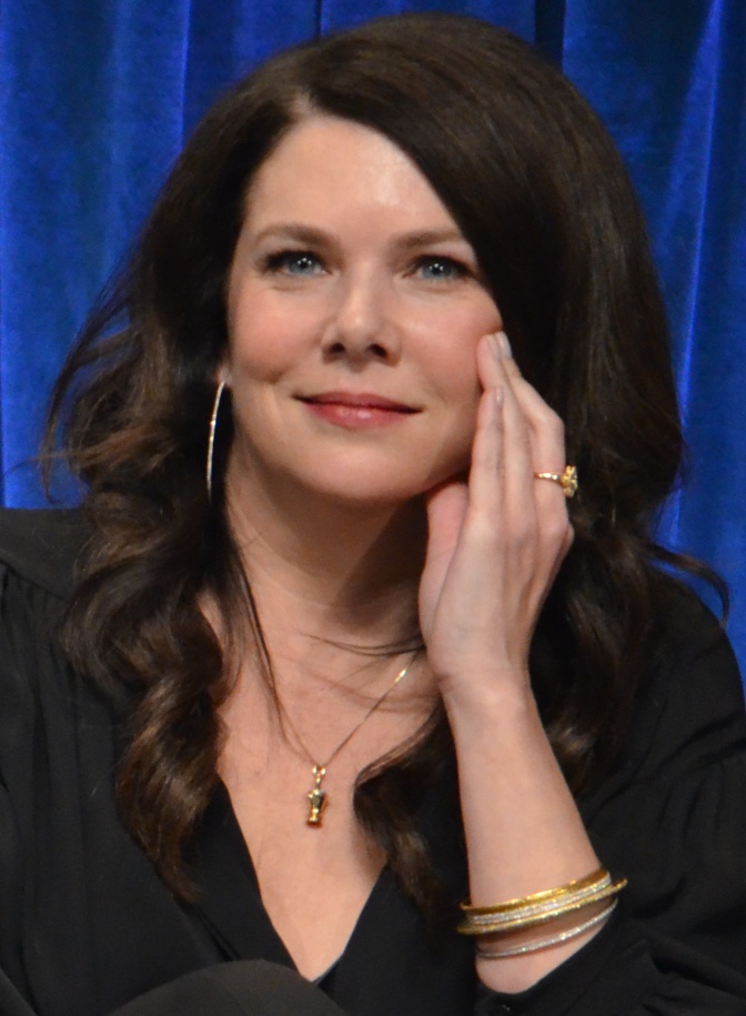 Lauren Graham schaut direkt in die Kamera und fasst sich mit der Hand ins Gesicht.