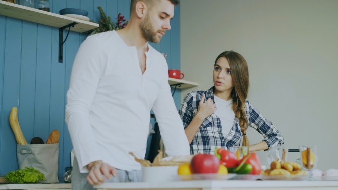 Ein heterosexuelles Paar steht in der Küche und streitet.