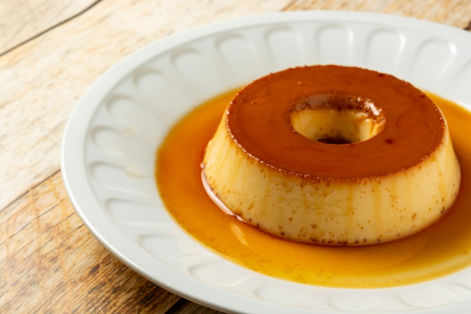 Ein Pudding mit einer karamellfarbenen Soße auf einem Teller