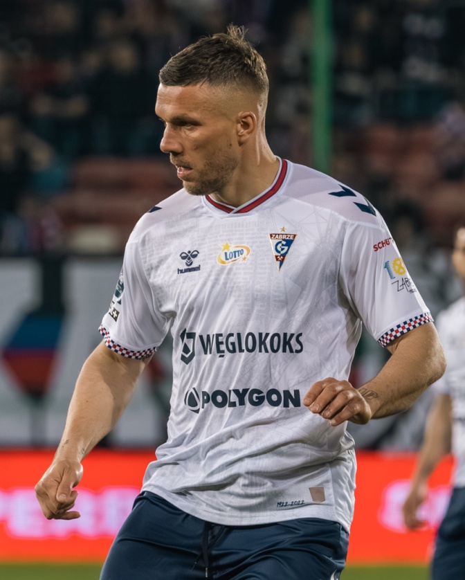 Lukas Podolski in einem weißen Trikot auf dem Fußballplatz.
