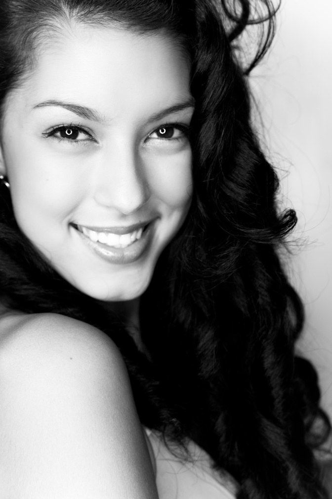 Schwarz-weiß-Foto von Rebecca Mir. Sie schaut seitlich in die Kamera und lächelt.