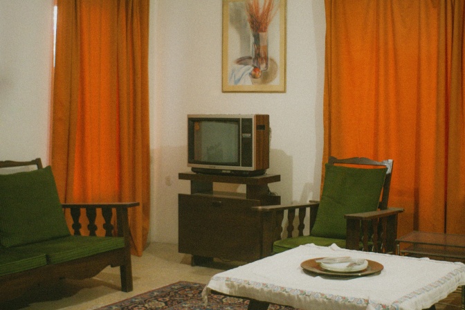 Ein Wohnzimmer im Stil der 1970er Jahre mit dem Fernseher im Mittelpunkt des Raumes