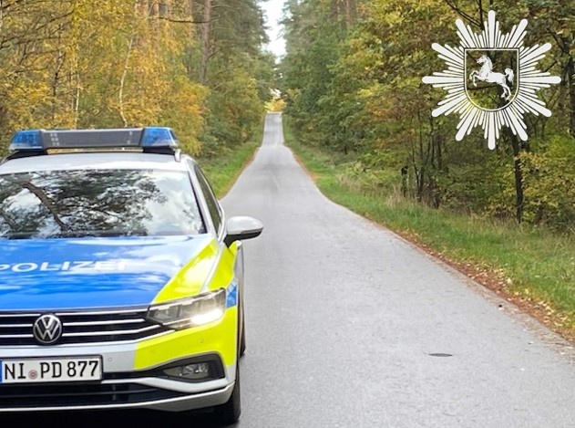 Ein seitlich an einem Waldweg geparktes Polizeiauto.