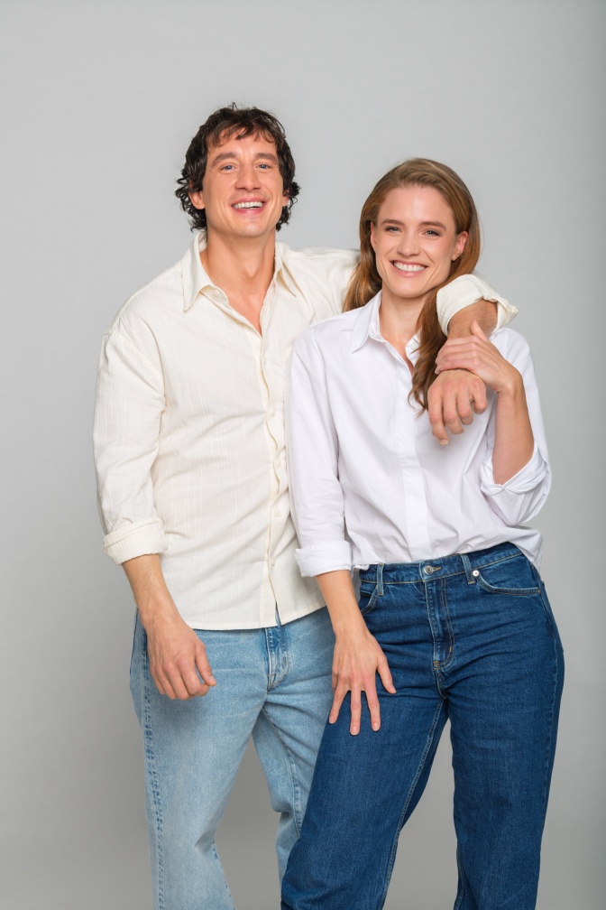 Laurence Rupp und Miriam Fussenegger tragen Jeans und weiße Hemden. Beide lehnen lächelnd aneinander und schauen in die Kamera.