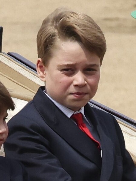 Prinz George sitzt in Anzug und Krawatte in einer Kutsche.