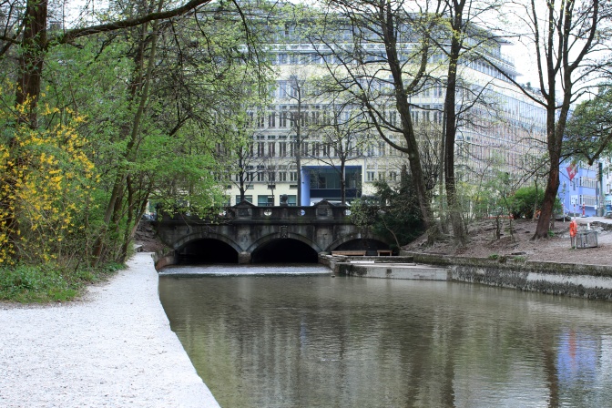 Der Eisbach verläuft flach unter einer Brücke hindurch.