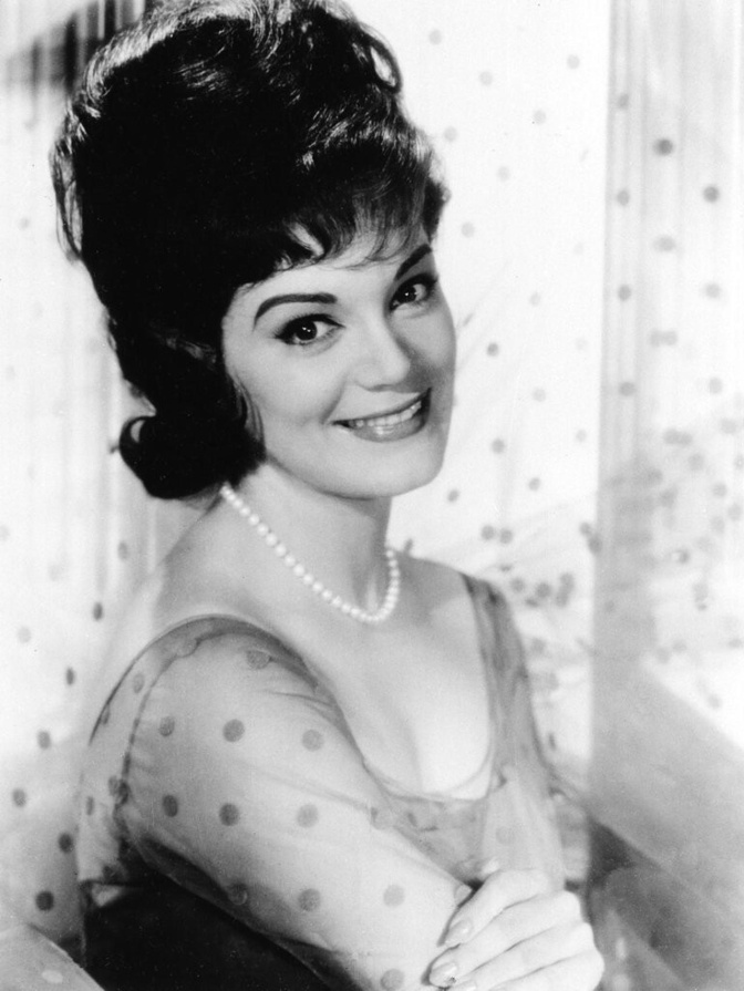 Schwarz-weiß-Foto der jungen Connie Francis mit hoch aufgetürmter Frisur in einer transparenten Bluse. Sie lächelt in die Kamera.