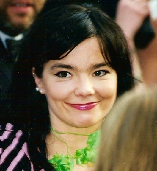Björk lächelt in die Kamera. Um sie herum stehen Menschen.