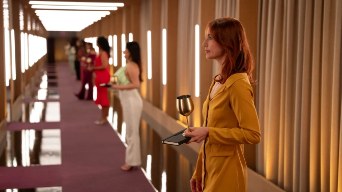 Frauen stehen vor den Eingangstüren der Pods. Sie haben jeweils ein goldenes Weinglas in der Hand und sind bereit, in die Pods einzutreten.