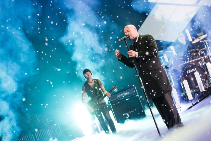 Die Band Unheilig auf der Bühne. Der Graf am Mikrofon. Die Bühne ist blau und türkis beleuchtet.