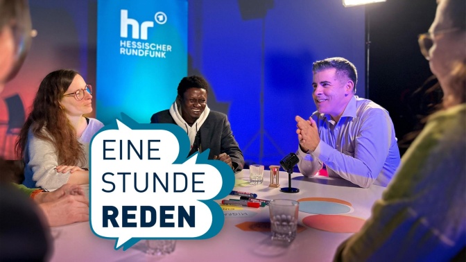 Mehrere Menschen sitzen in einem Radiostudio an einem Tisch und sind im Gespräch. Im Vordergrund der Schriftzug Eine Stunde reden.