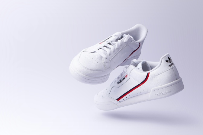 Weiße Sneaker von adidas mit einem schwarz-roten Streifen an der Seite.