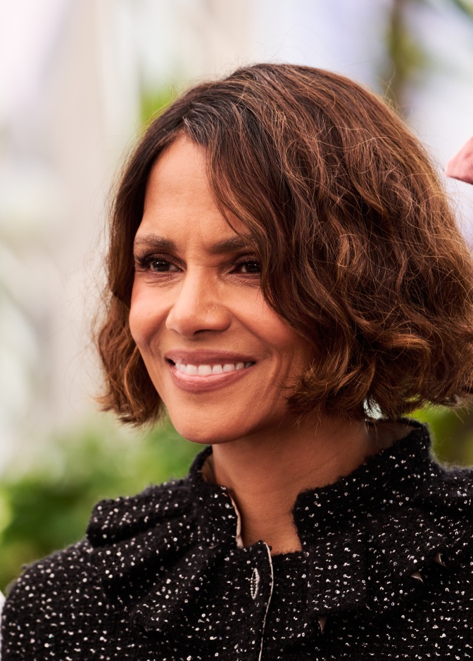 Halle Berry mit kinnlangen, gewellten Haaren. Sie lächelt und schaut seitlich an der Kamera vorbei.