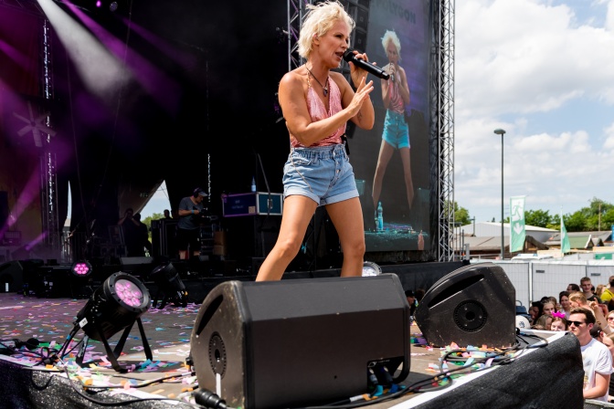 Michelle in einer kurzen Jeansshorts auf der Bühne. Sie singt in ein Mikrofon.