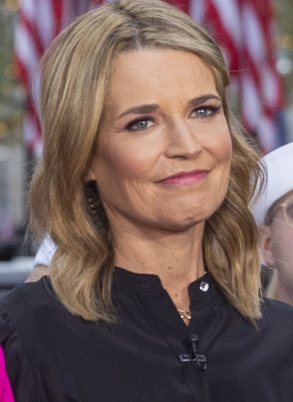 Savannah Guthrie mit kinnlangen blonden Haaren. Sie lächelt und schaut leicht seitlich an der Kamera vorbei.