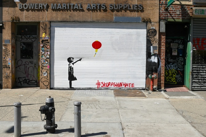 Ein Motiv von Banksy: Ein kleines Mädchen hat einen roten Ballon losgelassen, der davonschwebt. Das Motiv ist auf ein weißes Rolltor gesprayt.