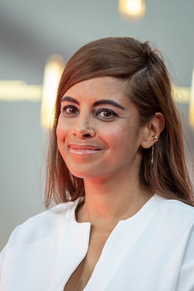 Collien Fernandes schaut mit leicht schief gelegtem Kopf lächelnd in die Kamera.