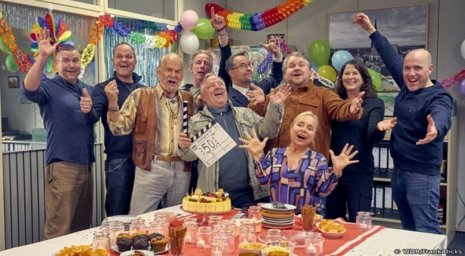 Das Team des Tatorts aus Münster steht in einem Raum mit Luftballons und Partydeko. Alle heben jubelnd die Arme in die Luft.