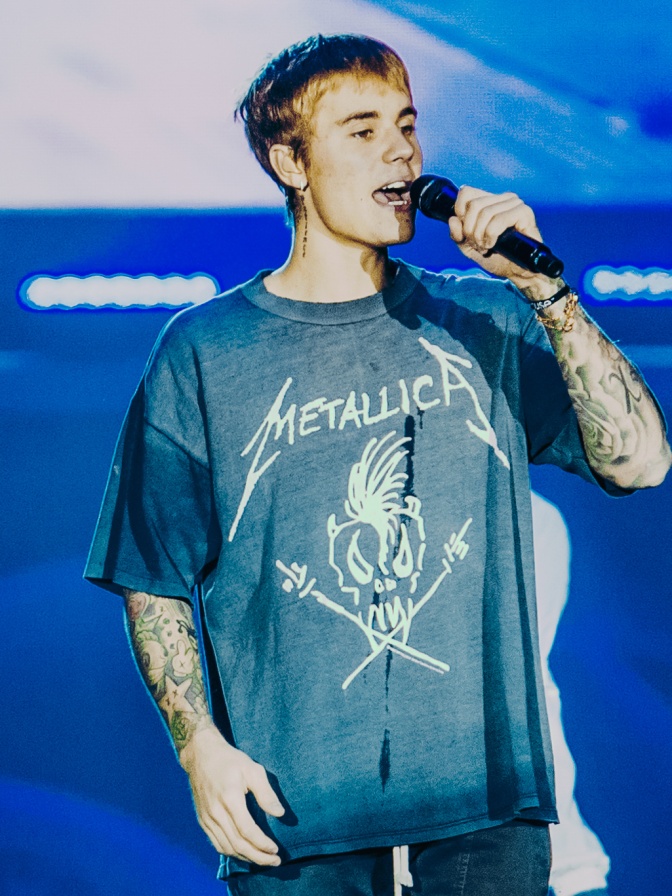 Justin Bieber auf der Bühne. Er trägt ein Metallica-Shirt und singt in ein Mikro.