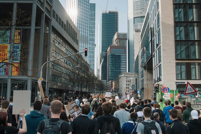 Eine Demo auf der Straße von Berlin, im Hintergrund Hochhäuser.