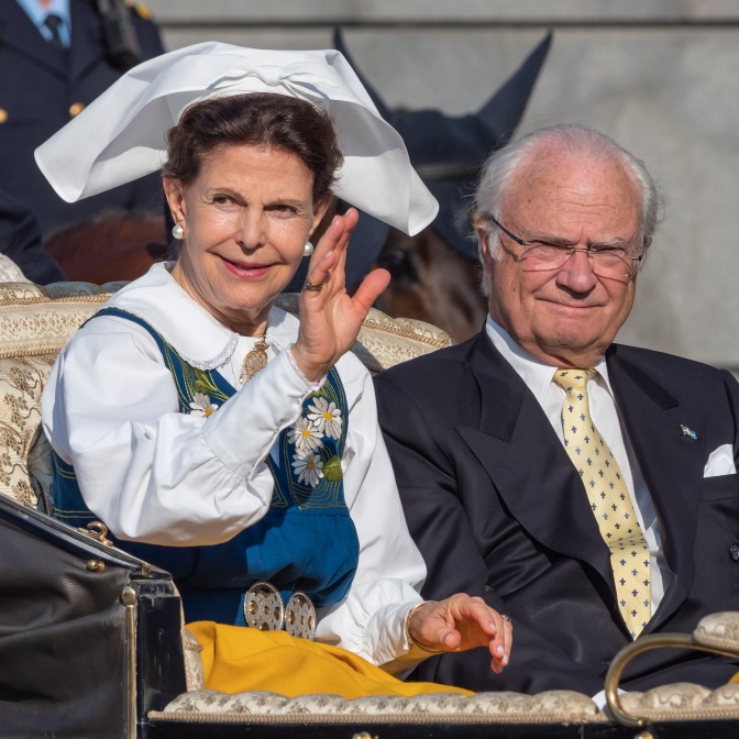 Carl Gustaf und Silvia von Schweden in einer Kutsche. Sie trägt Tracht und winkt.