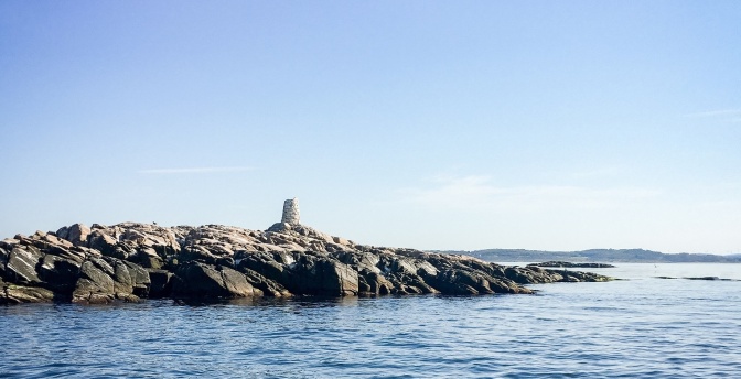 Eine kleine Insel bestehend aus Steinen und Geröll, in der Mitte ein kleiner Turm aus groben Steinen.