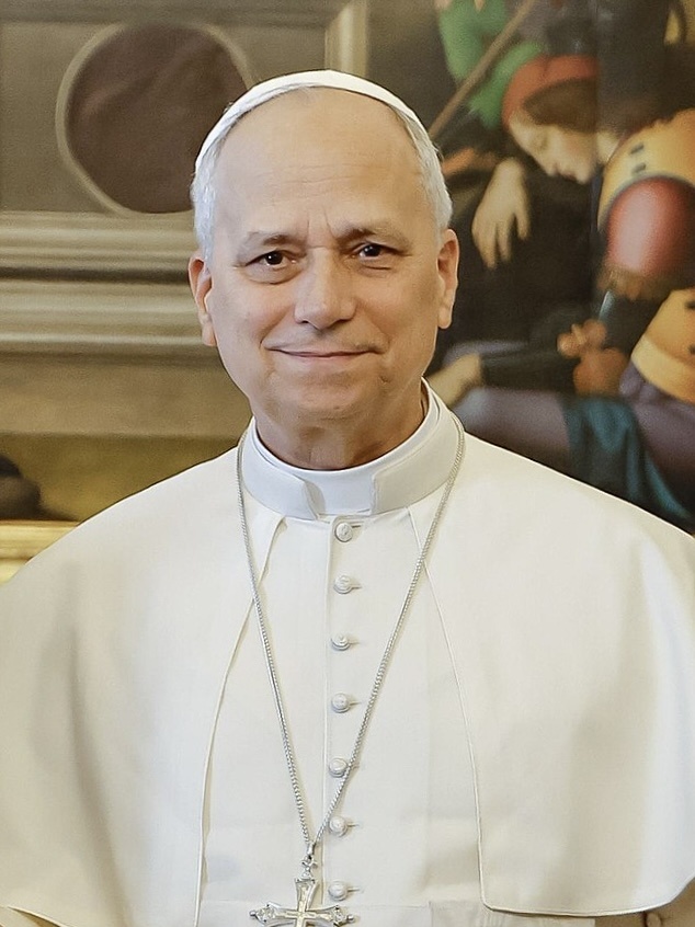 Papst Leo in weißer Kleidung mit einer kleinen weißen Kappe auf dem Kopf. Er trägt eine Kette mit einem großen Kreuz um den Hals.