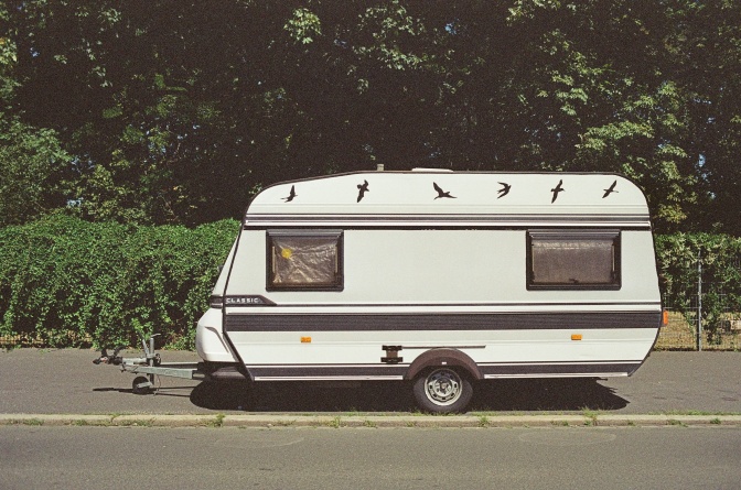 Ein weißer, mittelgroßer Wohnwagen, am Straßenrand geparkt.