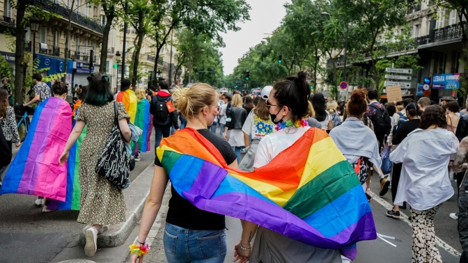 Eine Demo, die meisten Menschen sind von hinten zu sehen. Einige von ihnen haben Flaggen über den Schultern.