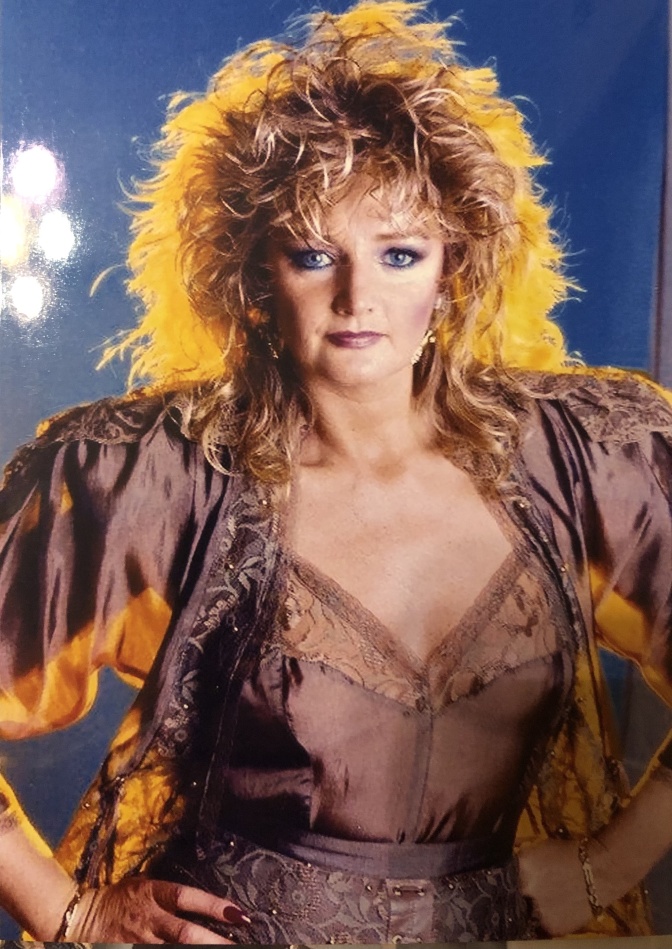 Bonnie Tyler mit lockigen roten Haaren in einem Bühnenkostüm im Stil der 1980er Jahre